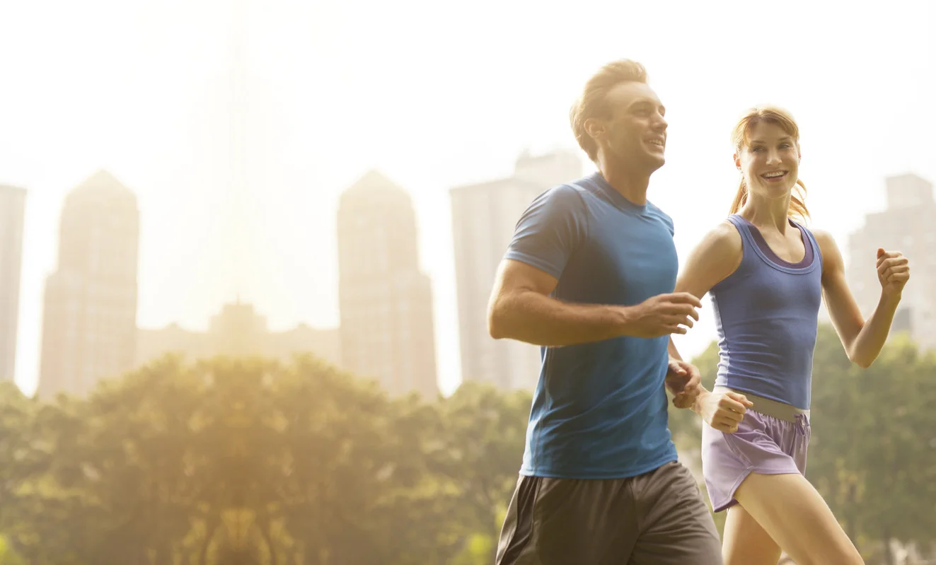 Active couple running comfortably together in a city park at sunrise